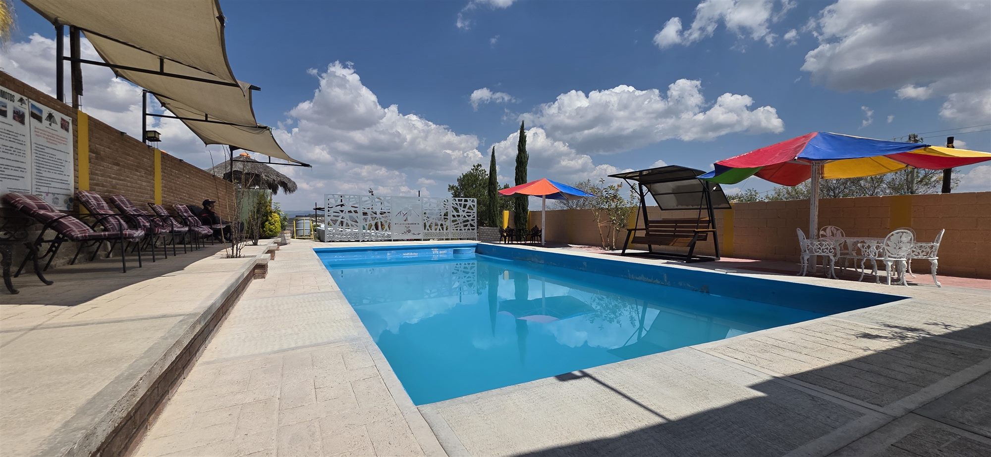 Alberca del Rancho Loma Bonita con camastros y sombrillas bajo cielo azul