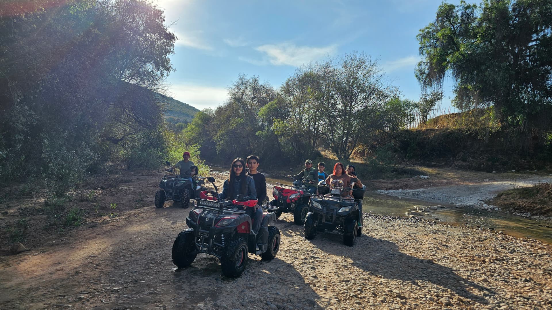 Grupo recorriendo en cuatrimotos un camino junto al arroyo