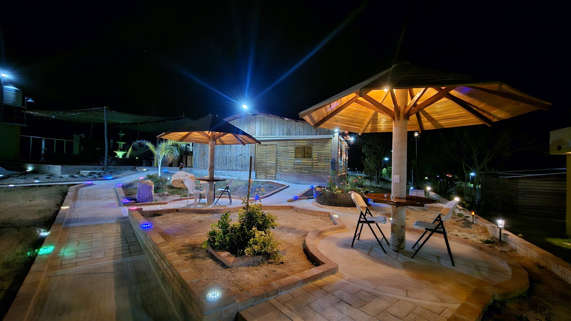 Jardín con palapas iluminadas durante la noche