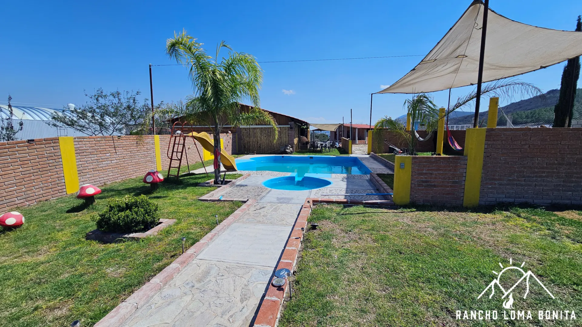 Alberca, chapoteadero y jardín del rancho bajo el cielo azul